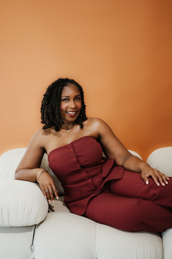 Kierra Dotson reclining on a cream sofa, arm resting on the armrest